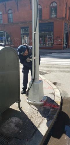 Clean Team repainting a traffic pole